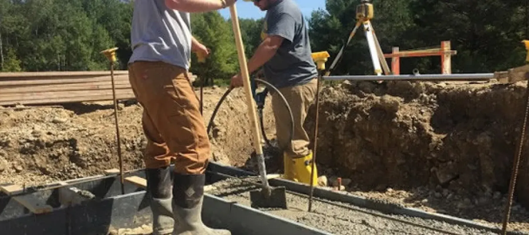 People mixing concrete in form for building foundation.