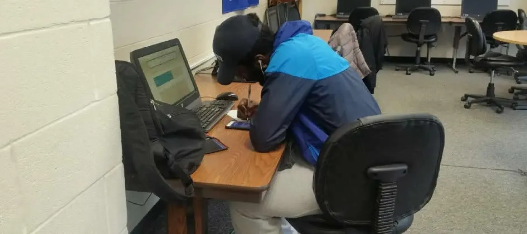 Student sitting at desk in front of computer working on assignment.