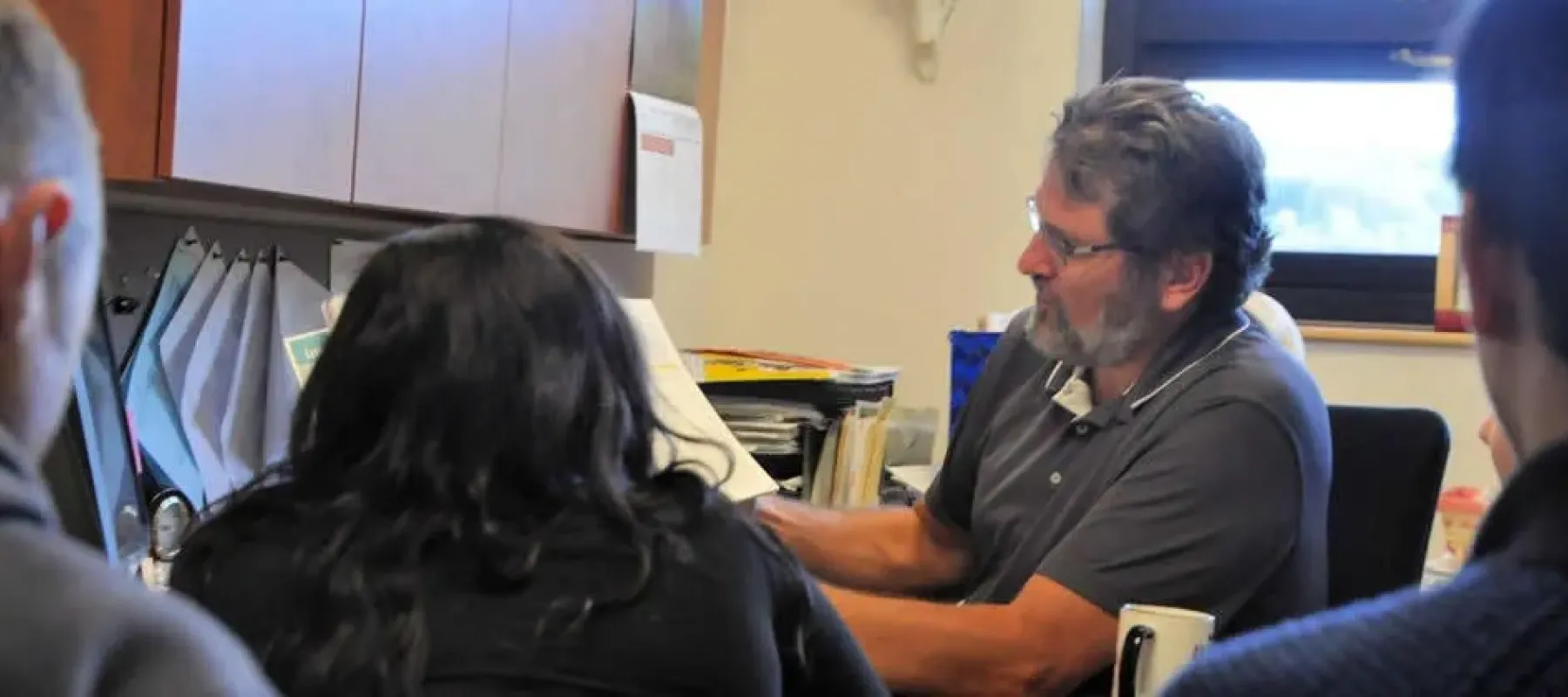 Students meeting with professor in office.