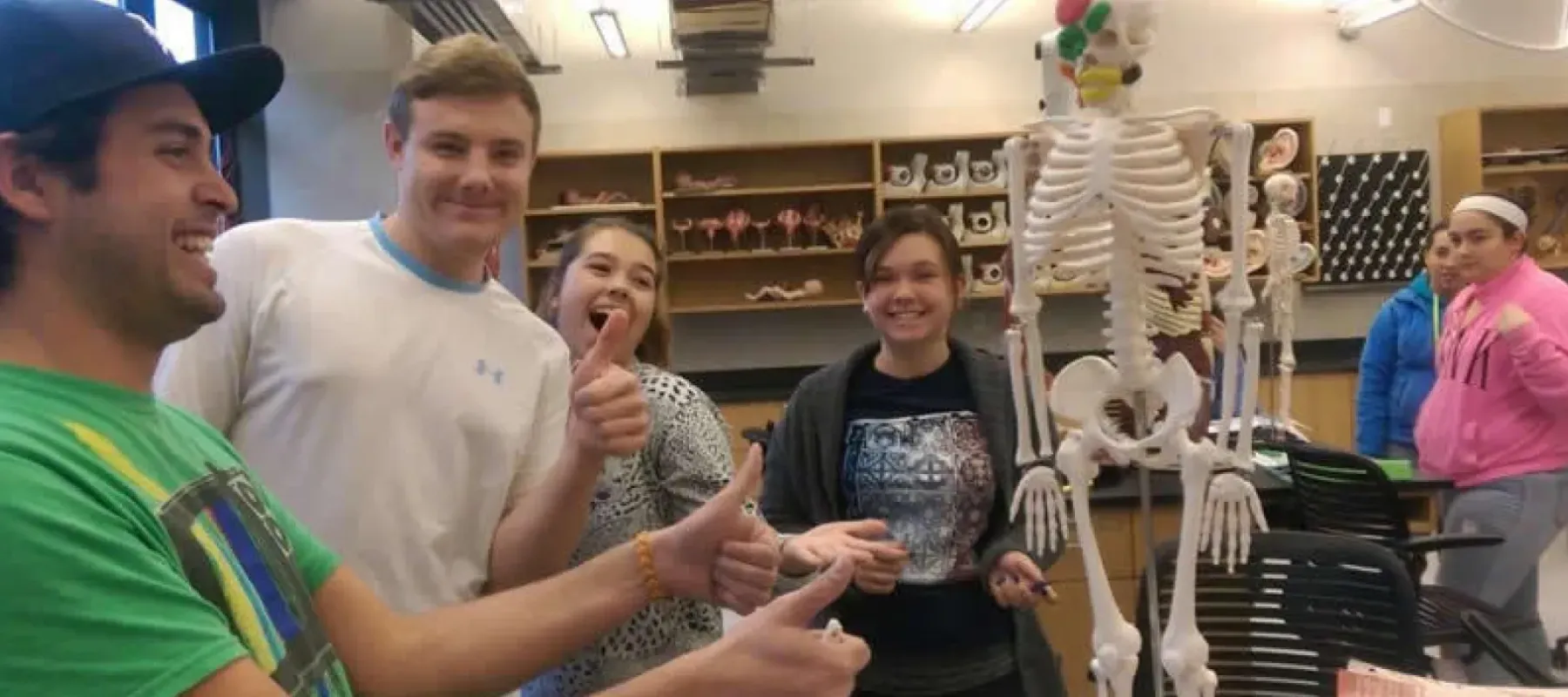 Students posing in classroom with skeleton.