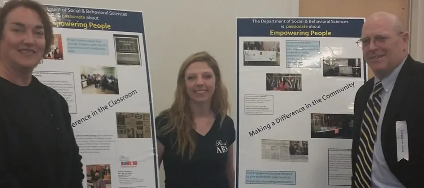 People standing by signs with information about the department of social & behavioral sciences.