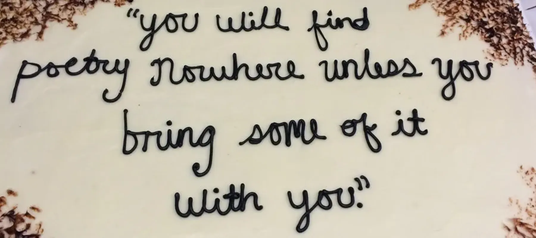 Cake with quoted text "you will find poetry nowhere unless you bring some of it with you" written in frosting.