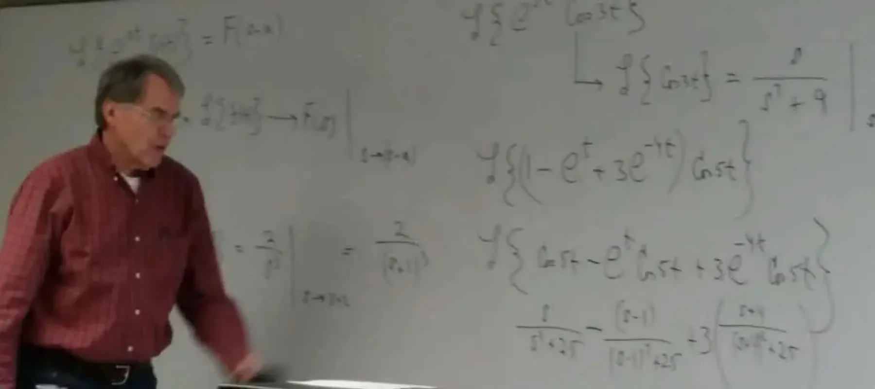 Professor in front of whiteboard with math equations.