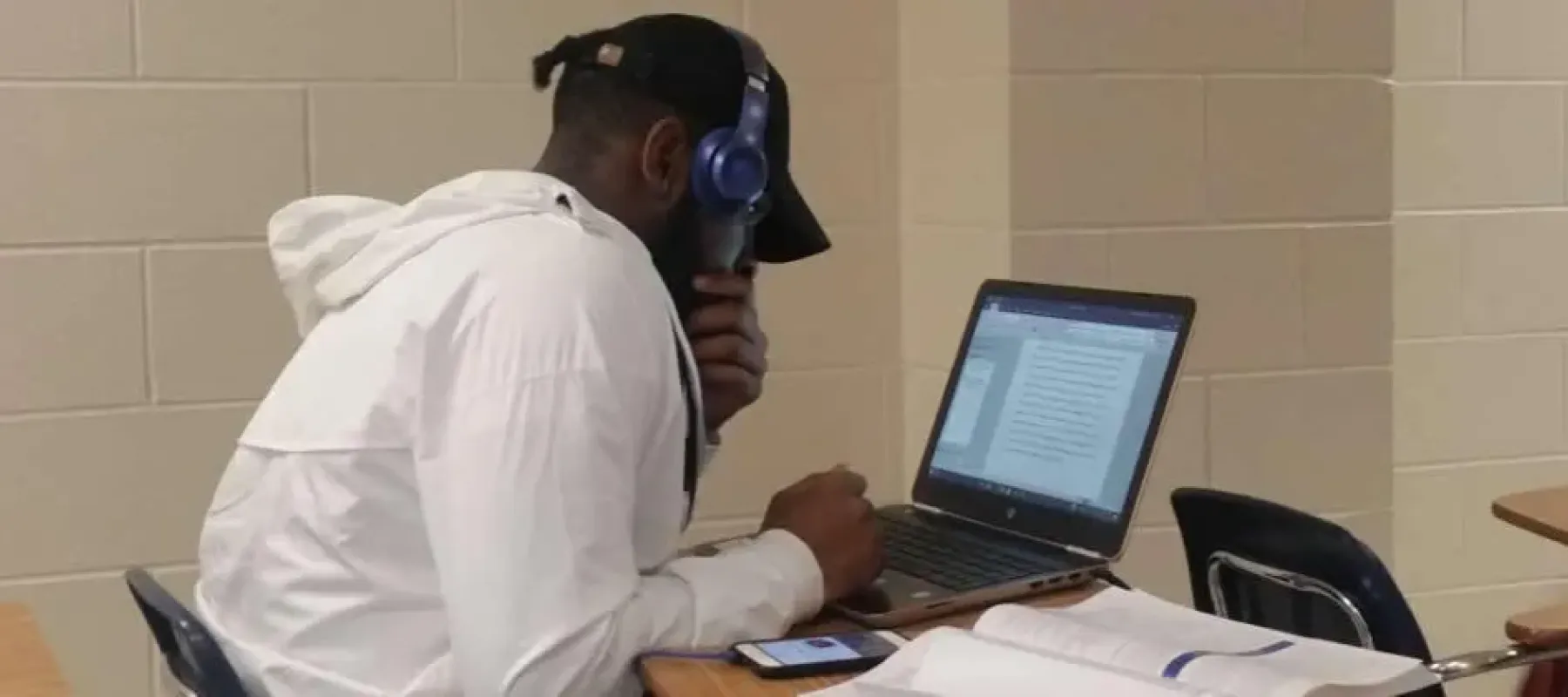 Student sitting at desk with a laptop working on a paper.