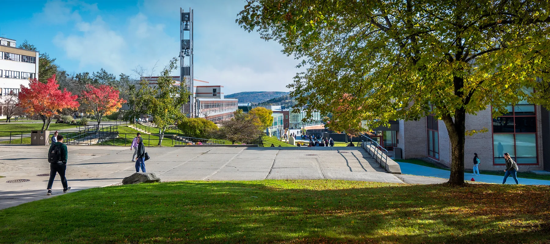 Wide view of inner campus walkway on a sunny day with students walking to class.