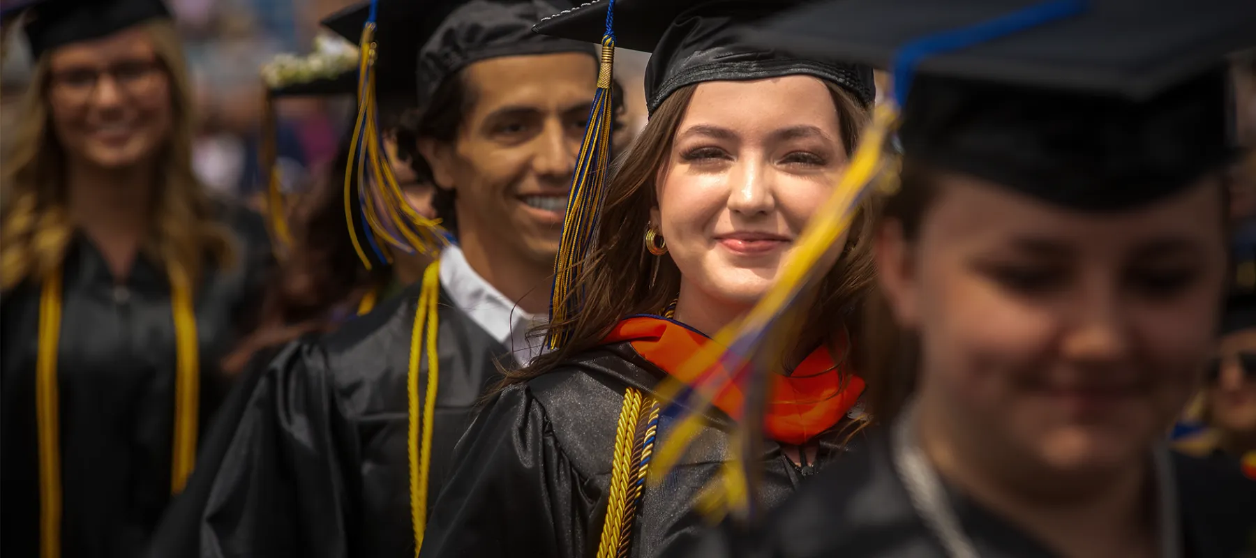 A student looking into the camera while walking at graduation.