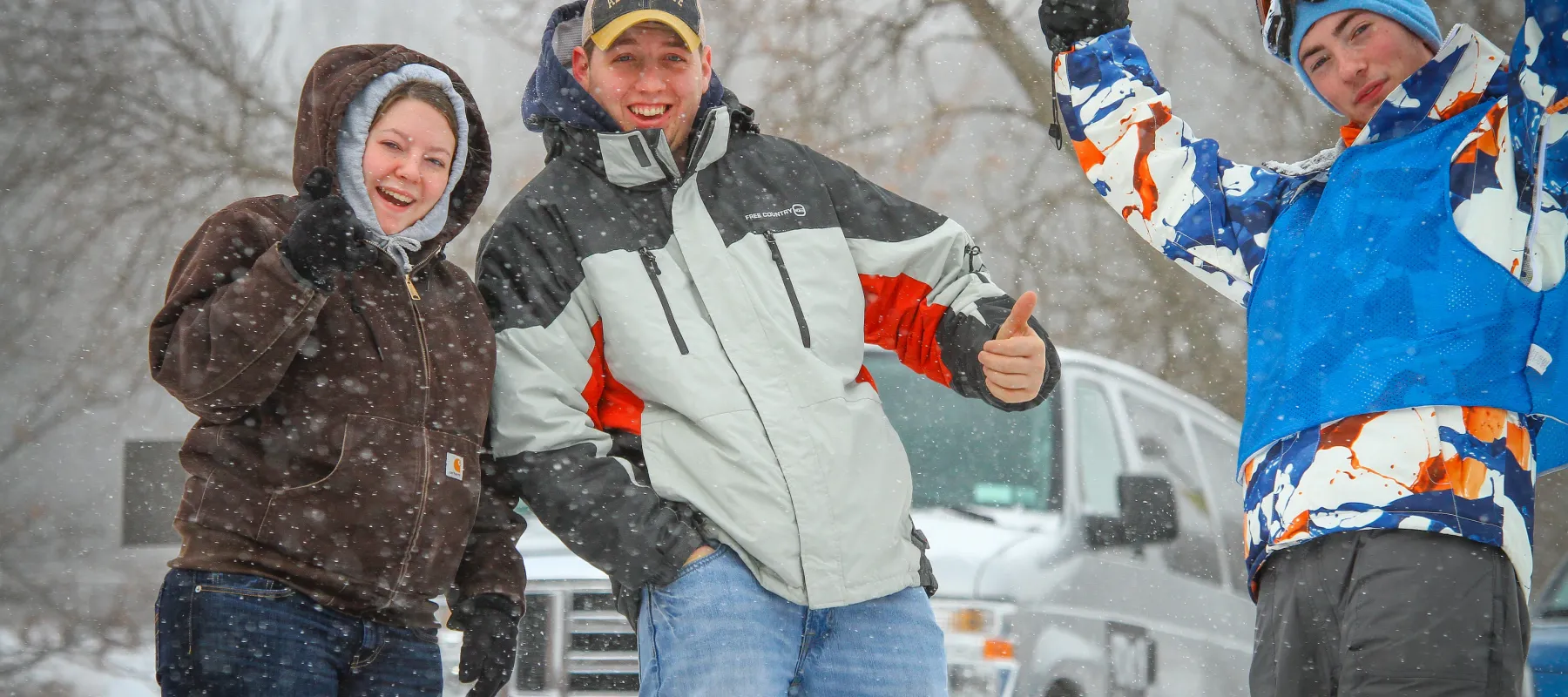 Three people posing outdoors in the snow.