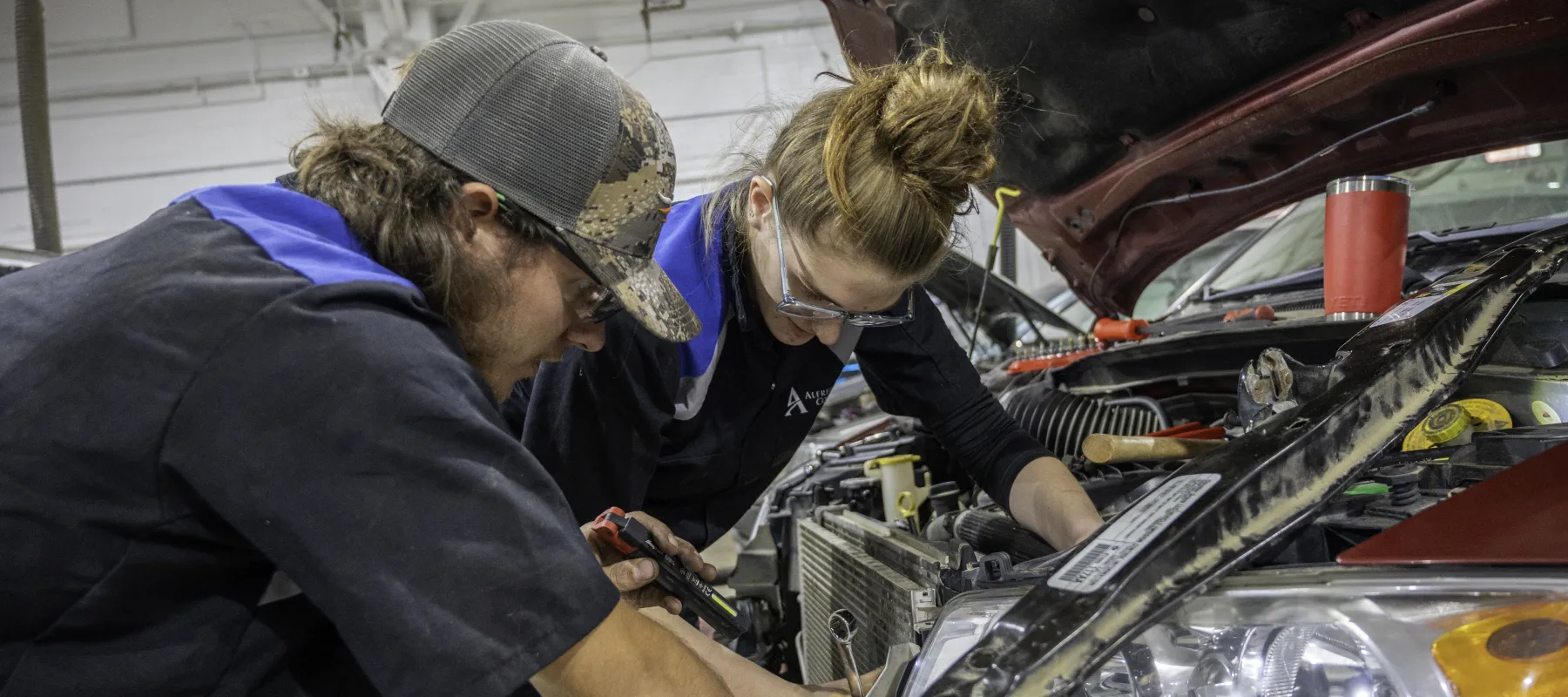 Two students working on the engine of a car