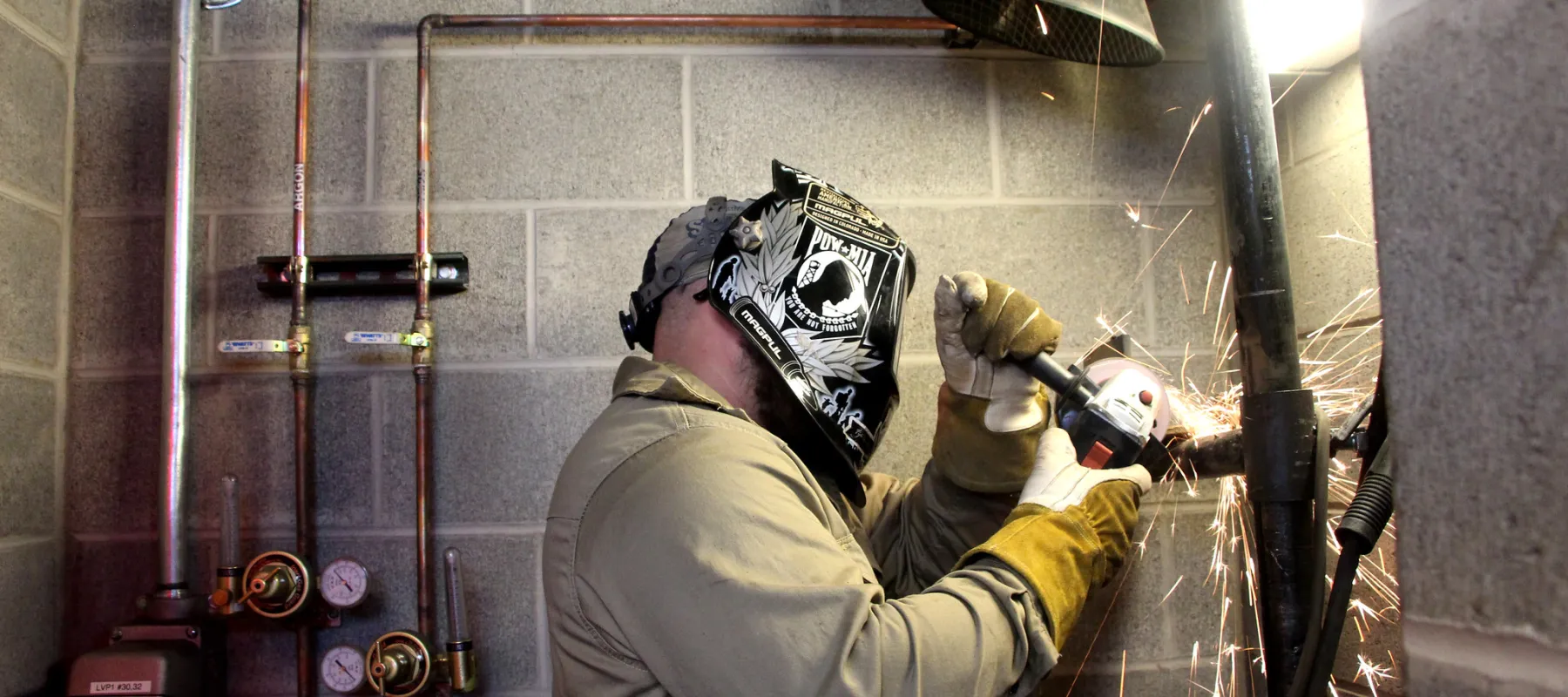 A student welding a piece of metal.