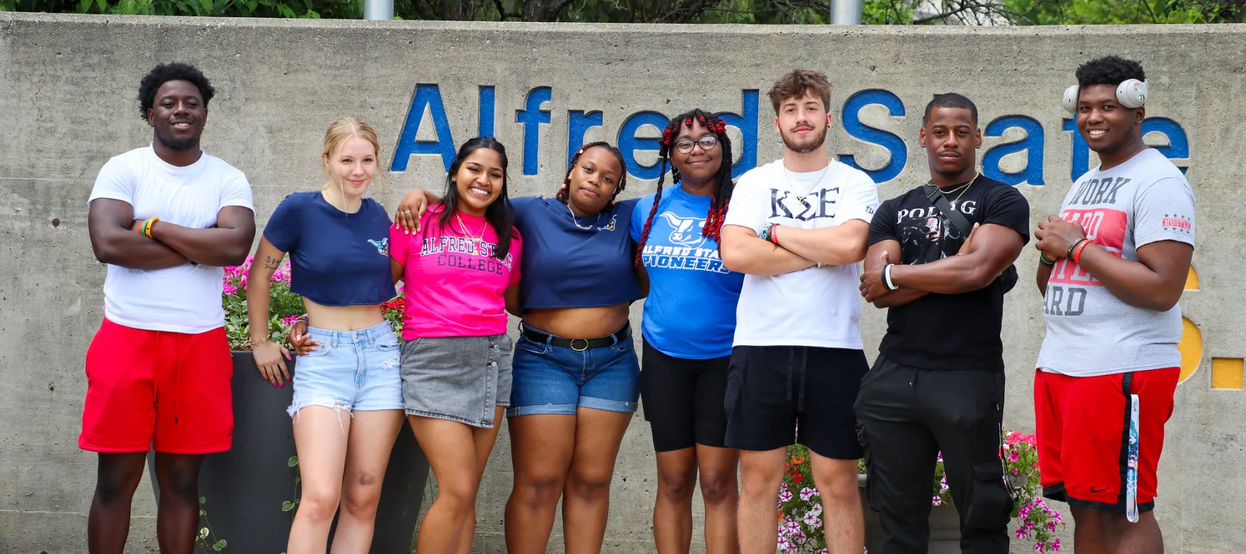 A group of students standing in front of the Alfred State entrance since.