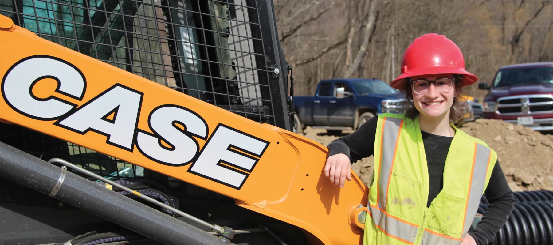 Construction Supervision student poses next to Case skid steer.