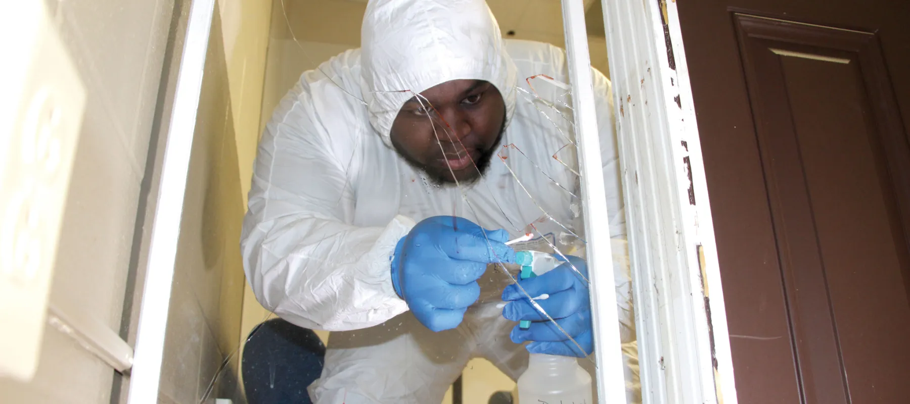 Criminal justice student collecting evidence from broken glass.