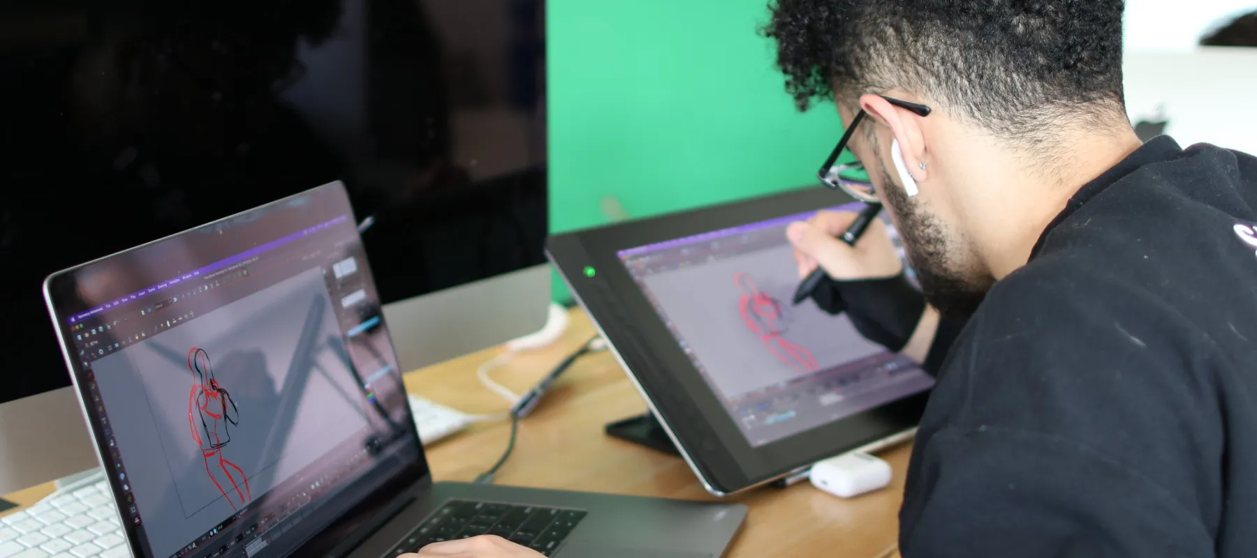 A student working on a drawing tablet and laptop for animation.