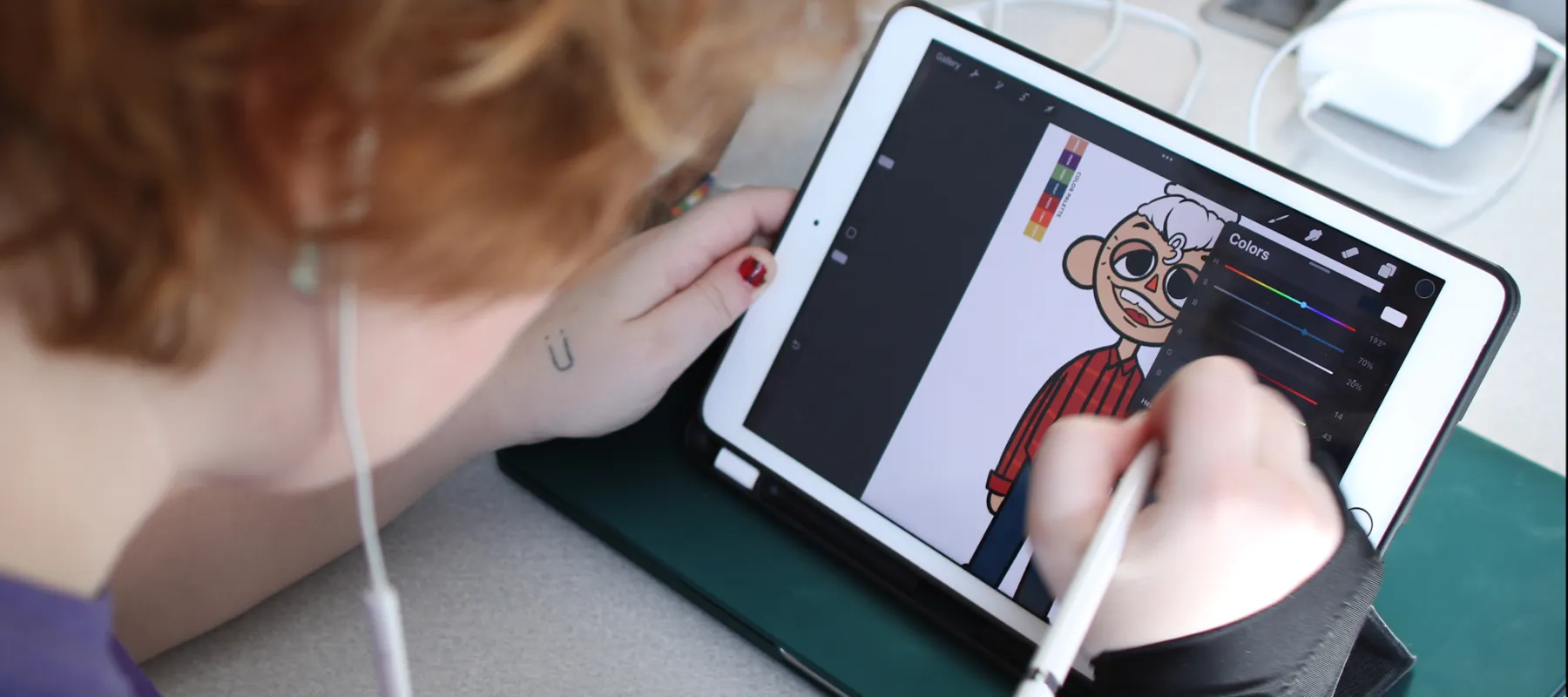 A student working on a digital tablet drawing a character.