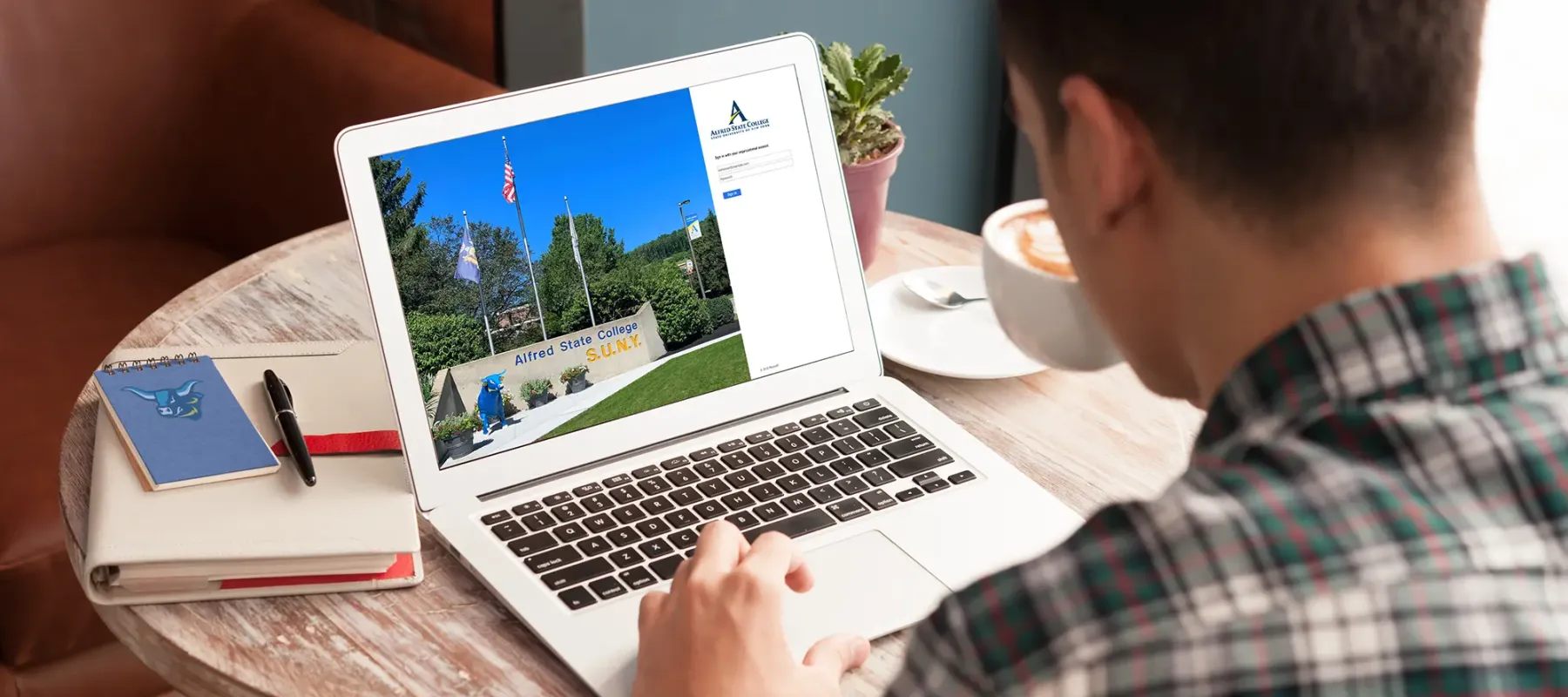 Photo of a male student sitting a table logging into their Alfred State account.