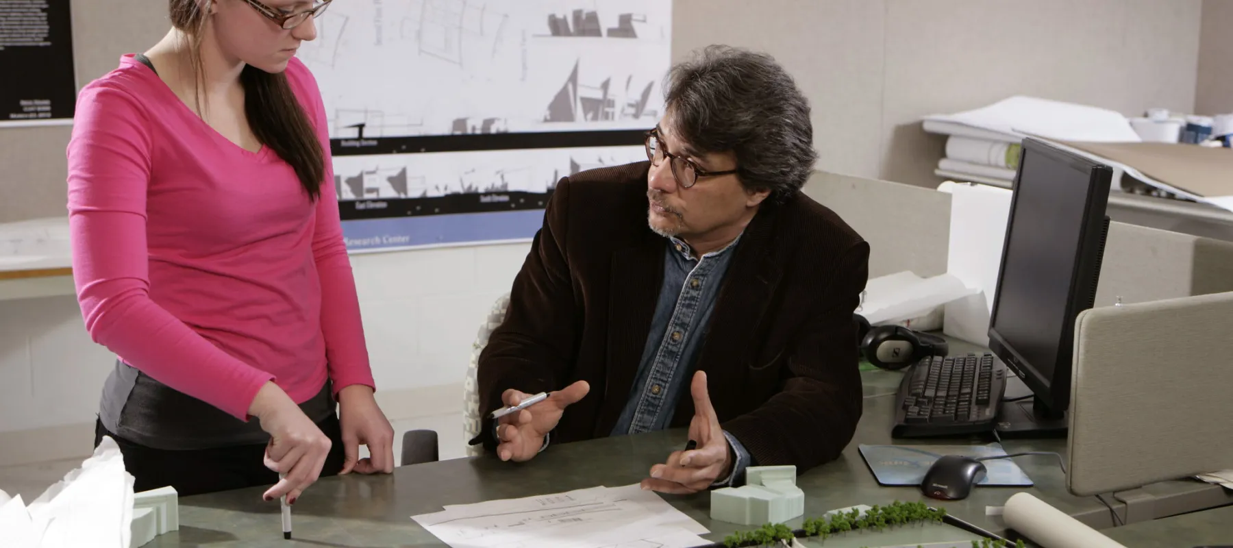 A professor and student having a conversation in front of an architectural model