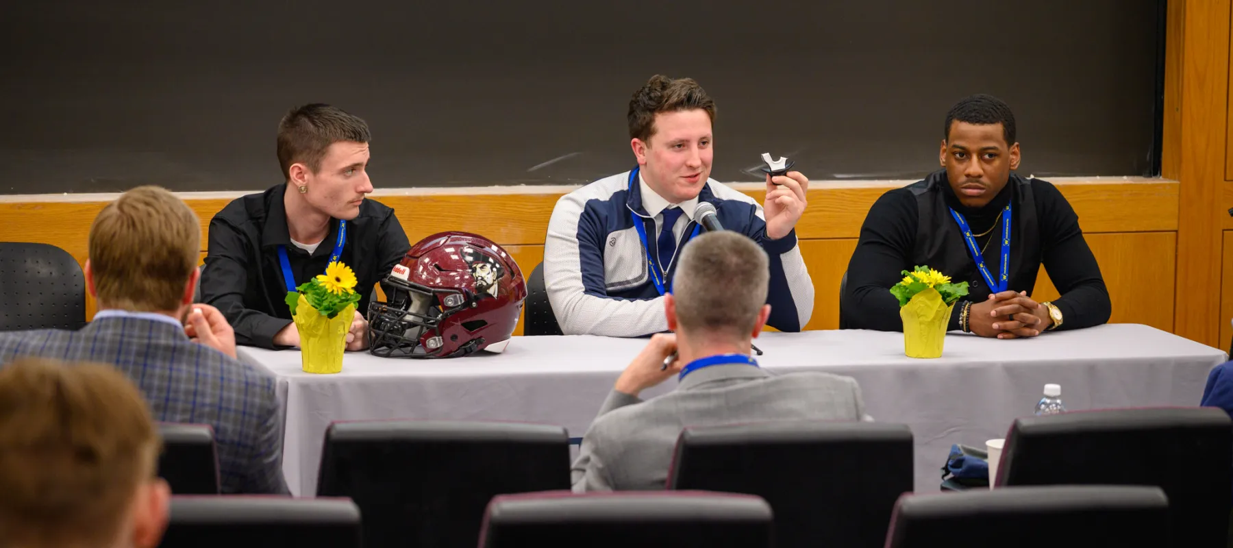 Three people sitting at table in the front of a room talking to an audience.
