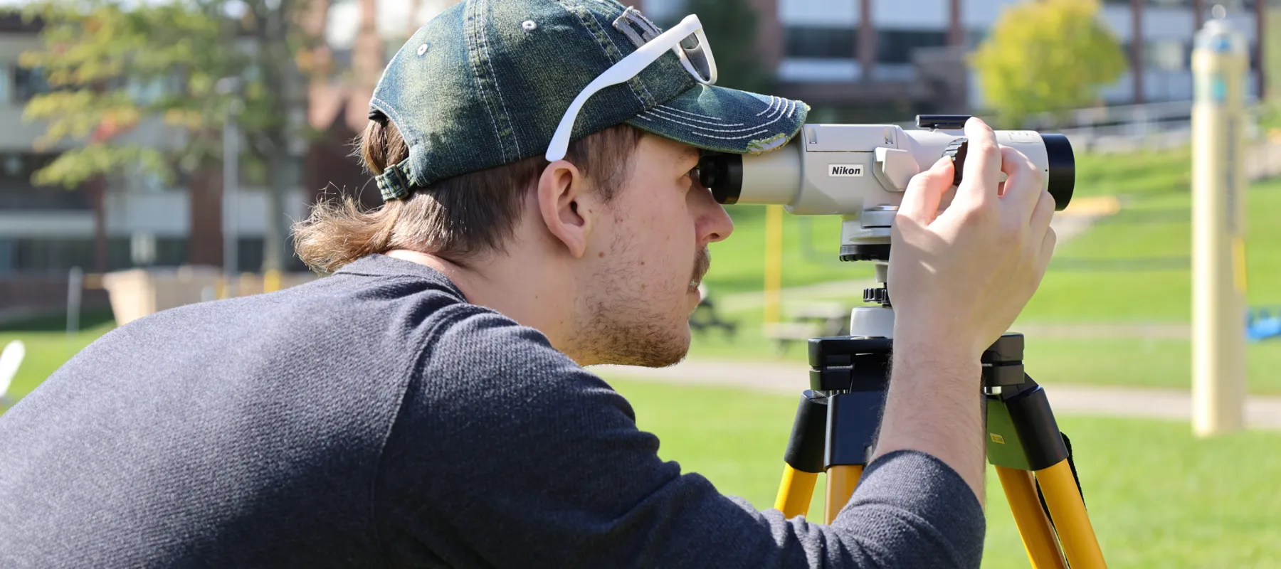 Surveying student practicing outdoors on campus.