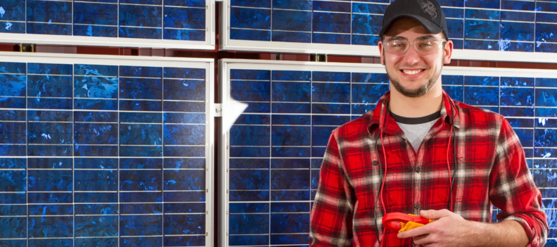 Student posing for photo with solar panels in the background.