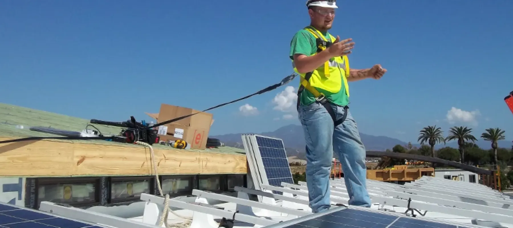 Man working on building roof installing solar panels.