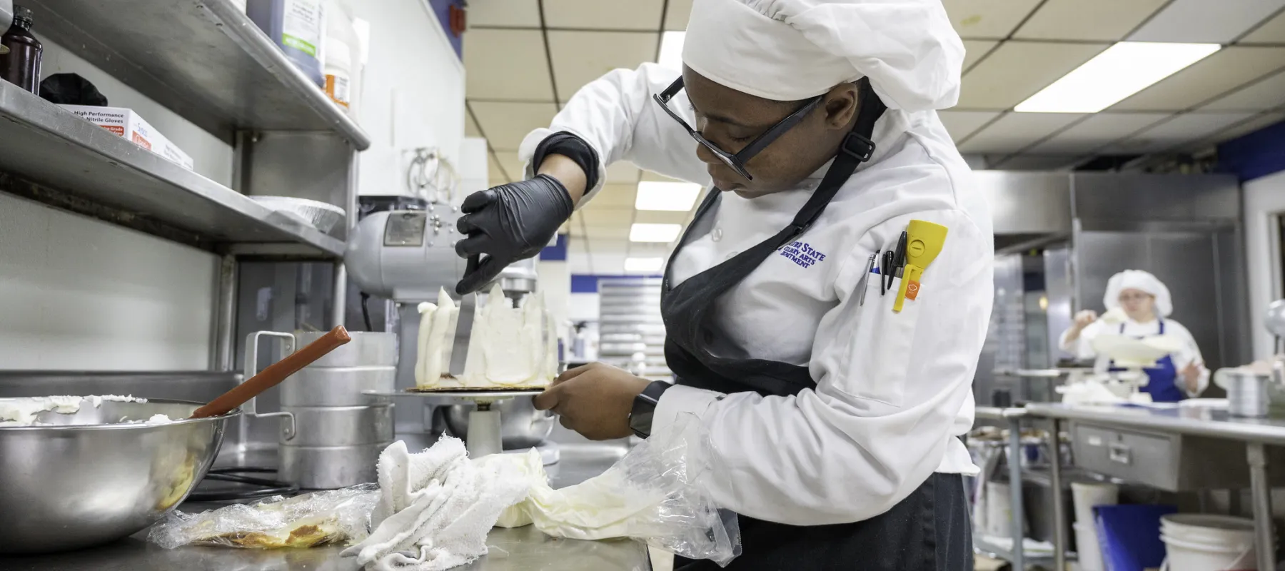 Culinary arts student in the kitchen frosting a cake.