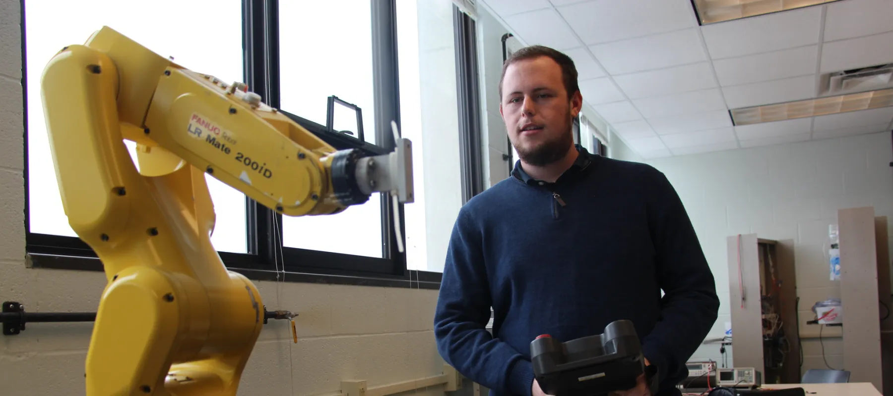 Electrical Engineering Technology student working with robotic machine.