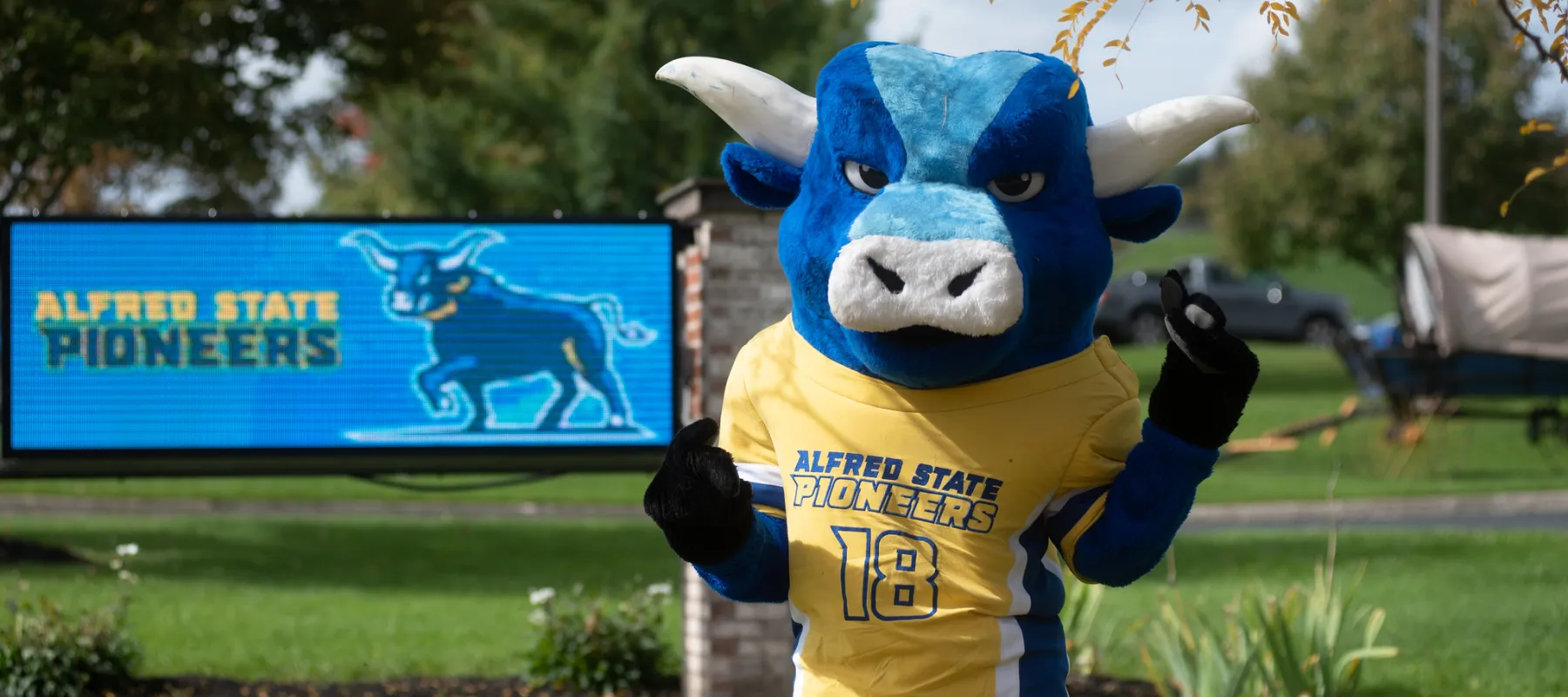 Alfred State's mascot standing in front of an electronic sign