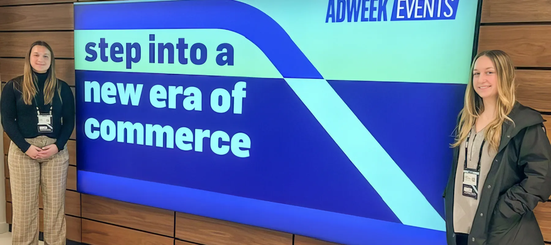 Marketing students posing in front or digital sign that reads "Step into a new era of commerce."