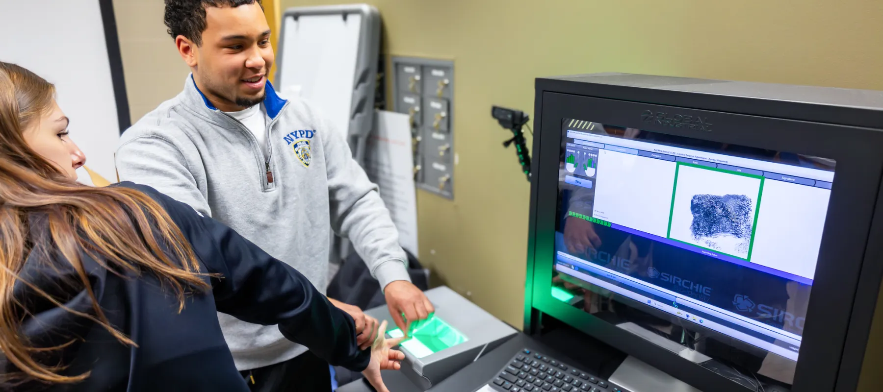 A student finger fingerprinting another student in a Forensic Science Lab.