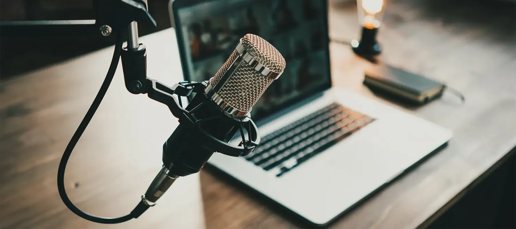 Photo of a mic with a computer in the background at a desk.