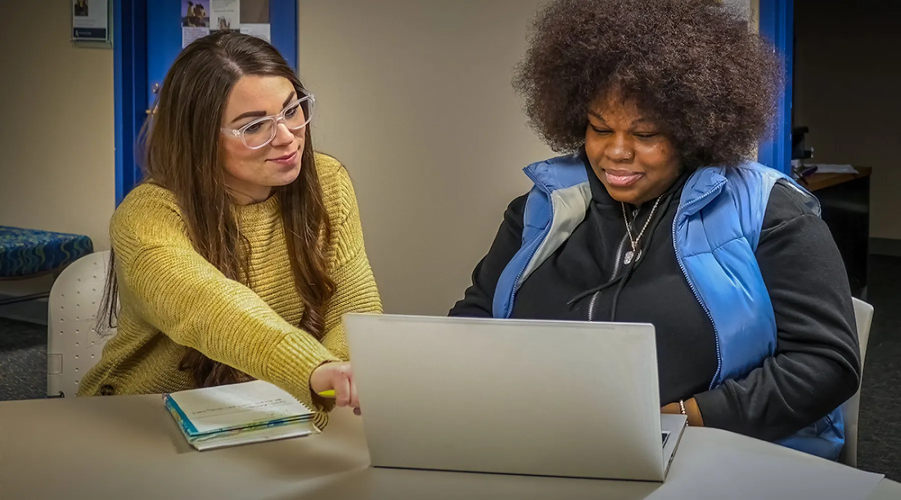 A student working on a computer with a professional mentor.