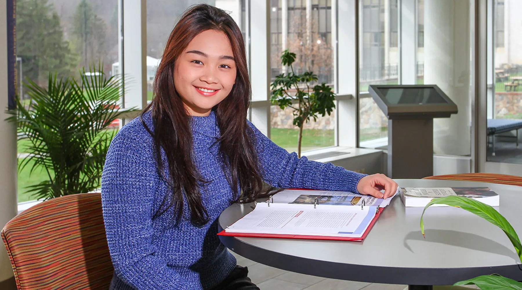 Student sitting at table with binder in Student Leadership Center.
