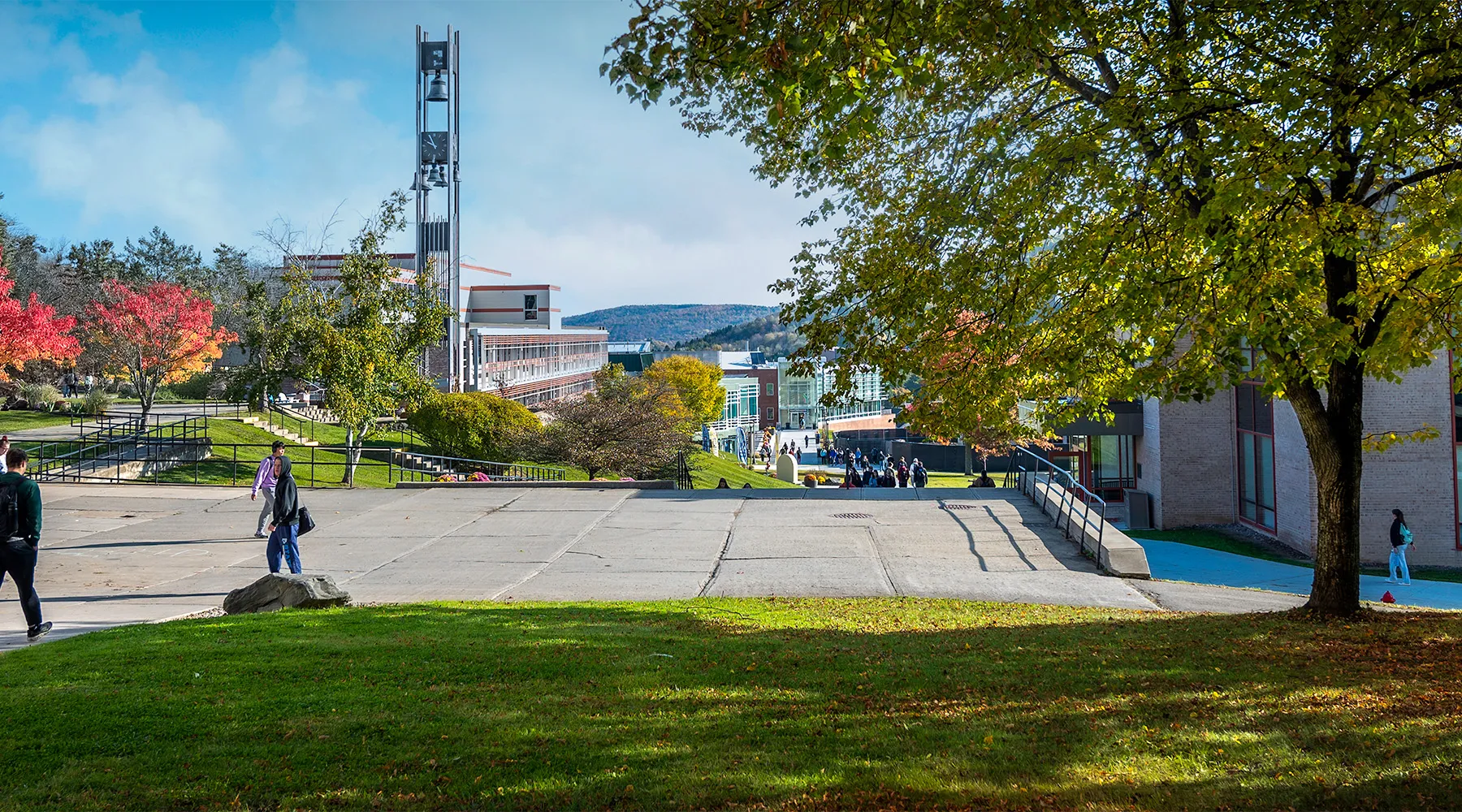 Wide view of inner campus walkway on a sunny day with students walking to class.