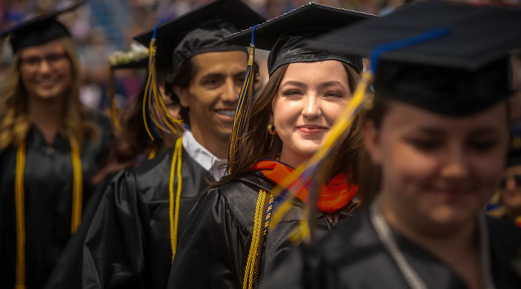 A student looking into the camera while walking at graduation.
