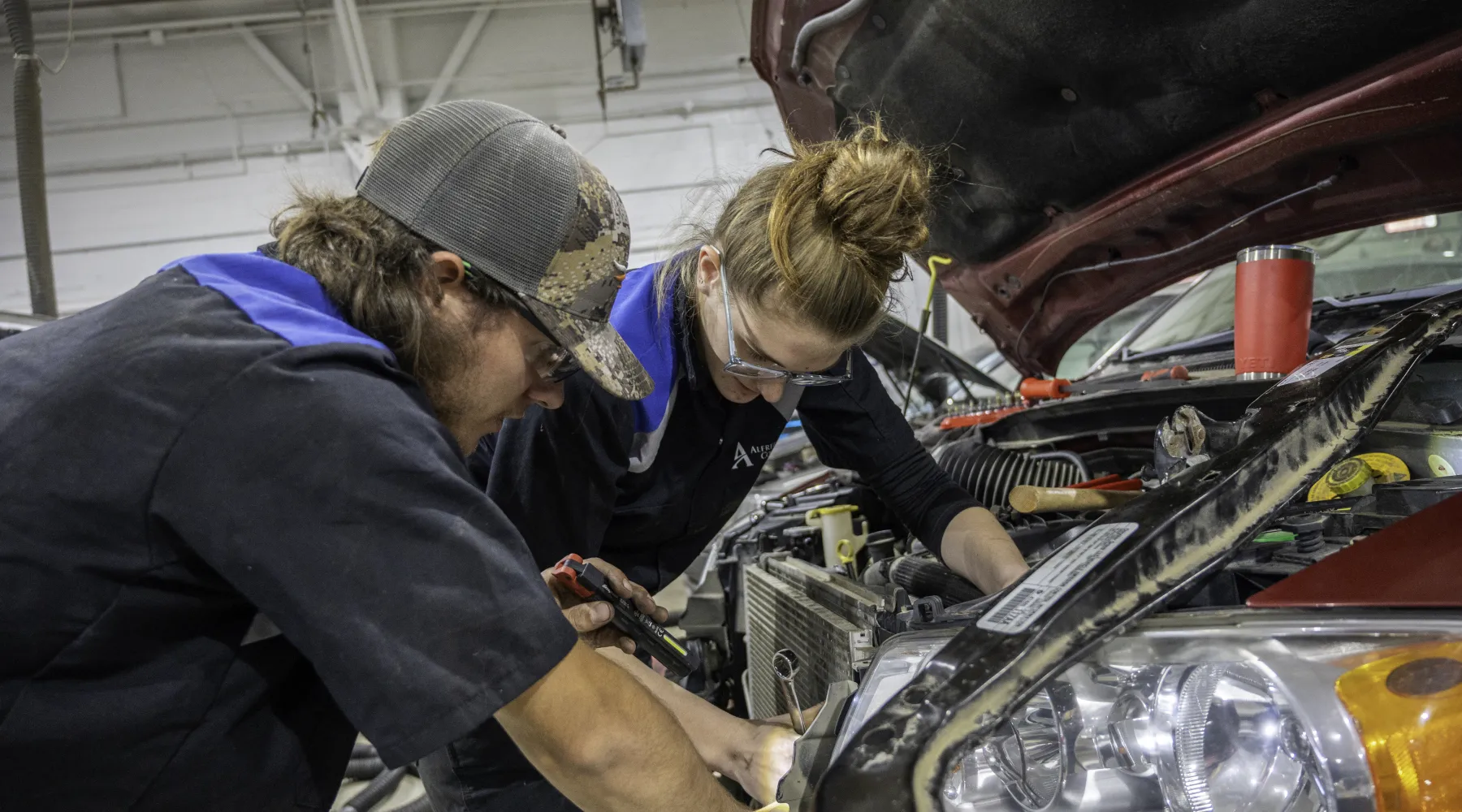 Two students working on the engine of a car
