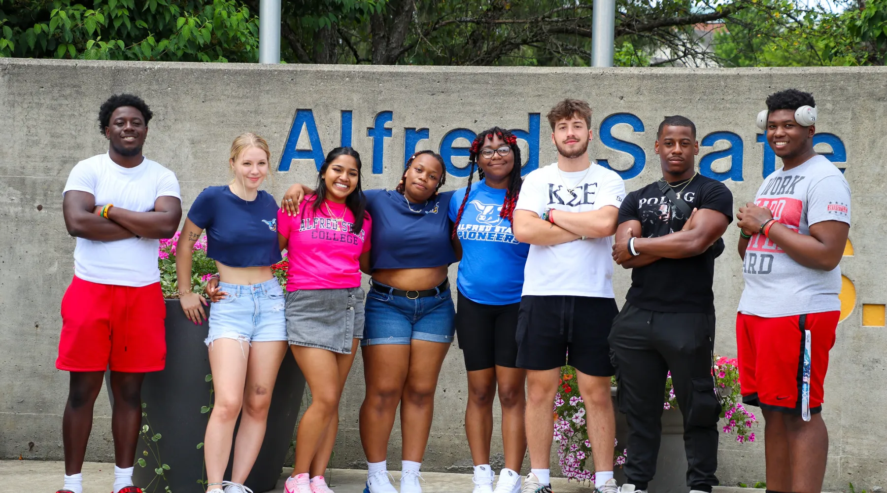 A group of students standing in front of the Alfred State entrance since.