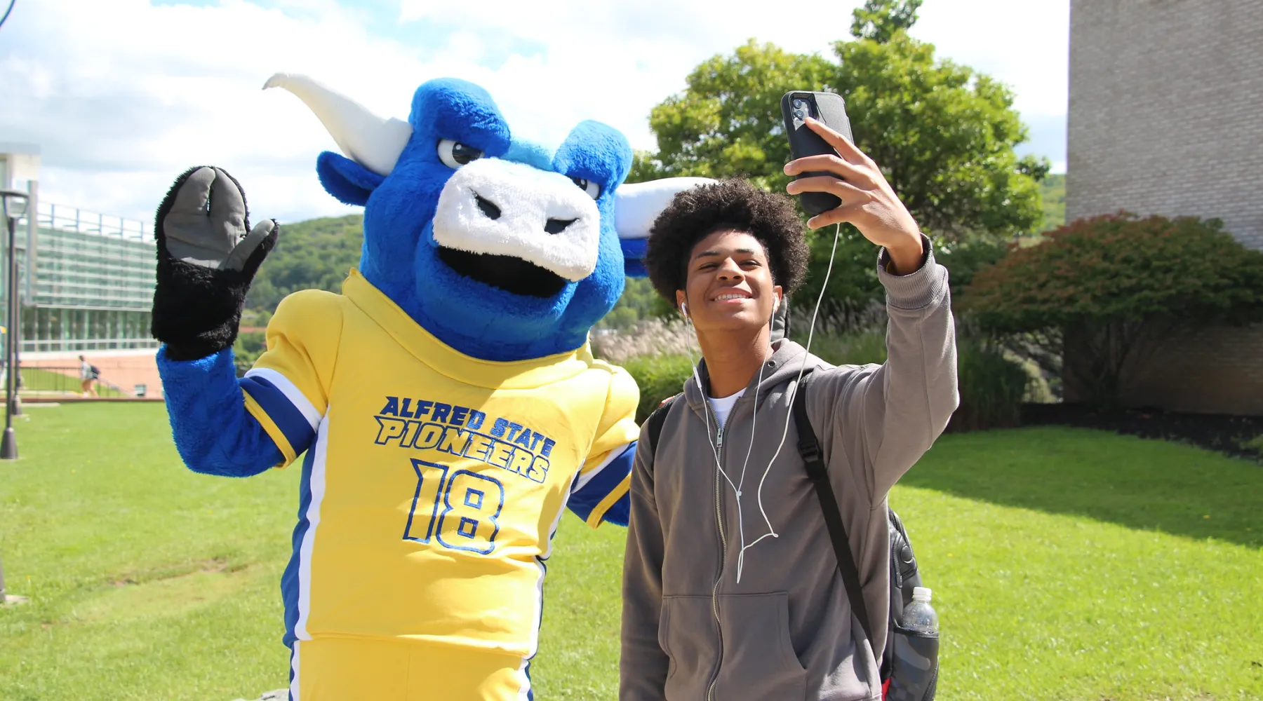 A student taking a selfie with Alfred State's mascot, Big Blue