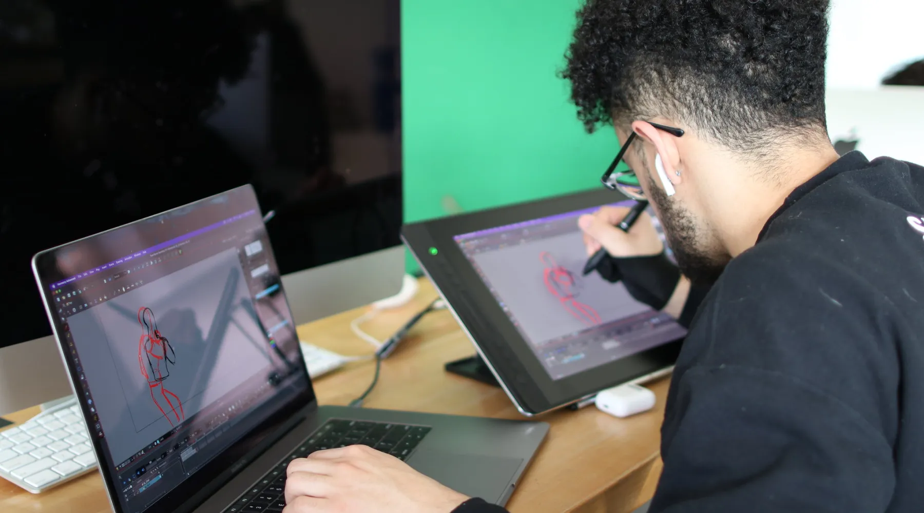 A student working on a drawing tablet and laptop for animation.