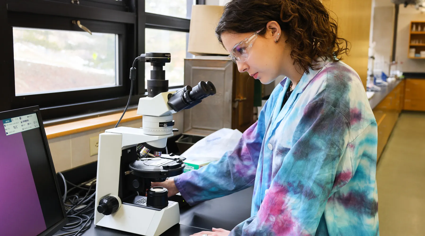 A student looking through a microscope in a lab.