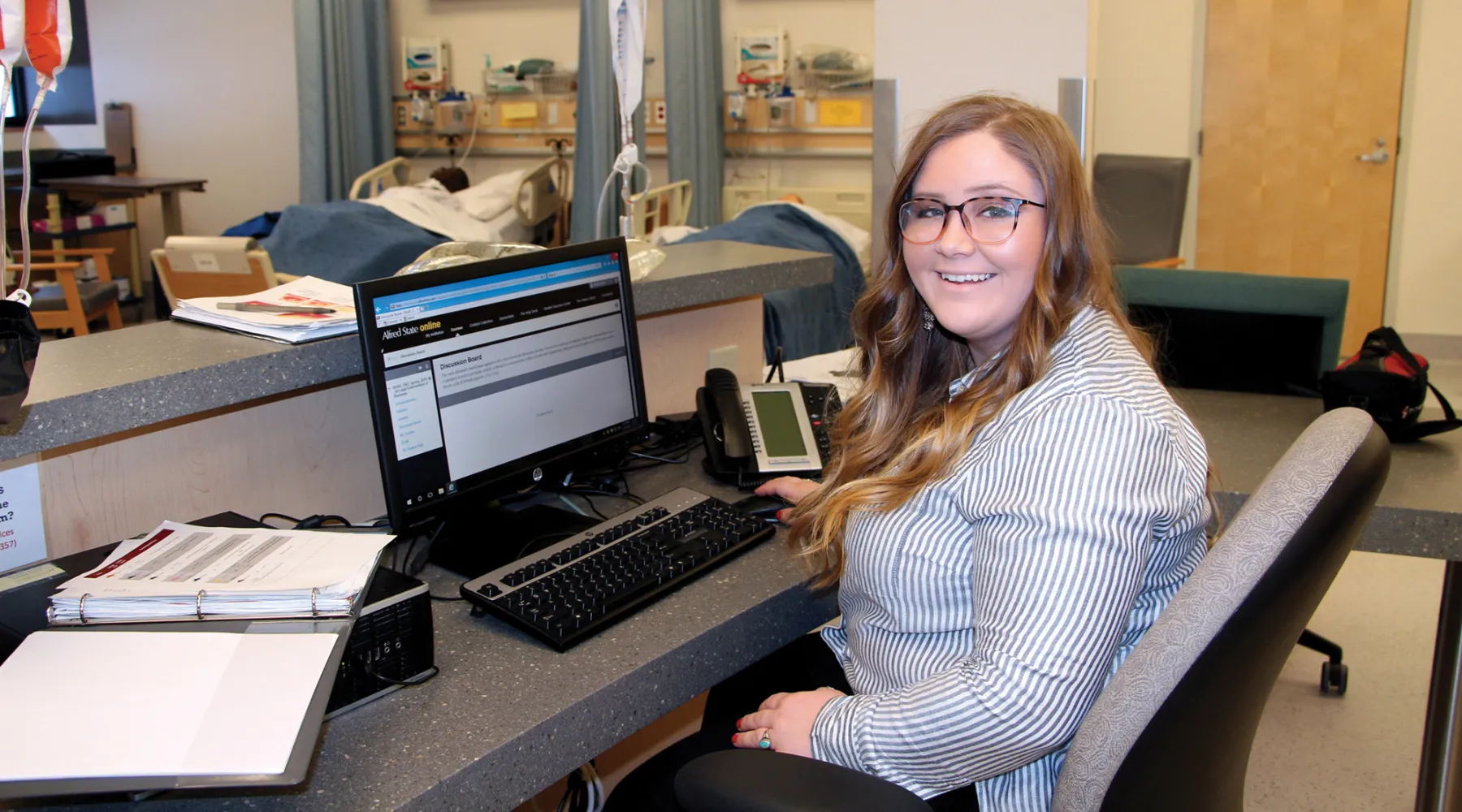 A student sitting at a desk in a hospital check-in.