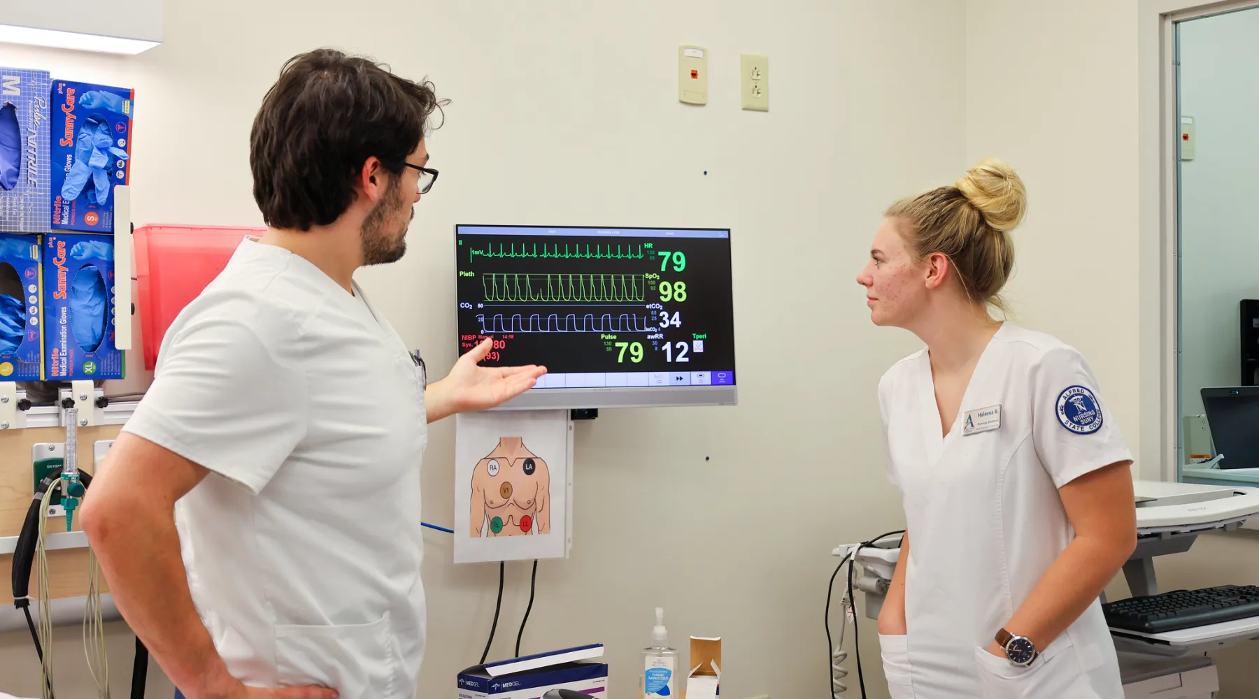 Two nursing students looking at monitor in hospital environment.
