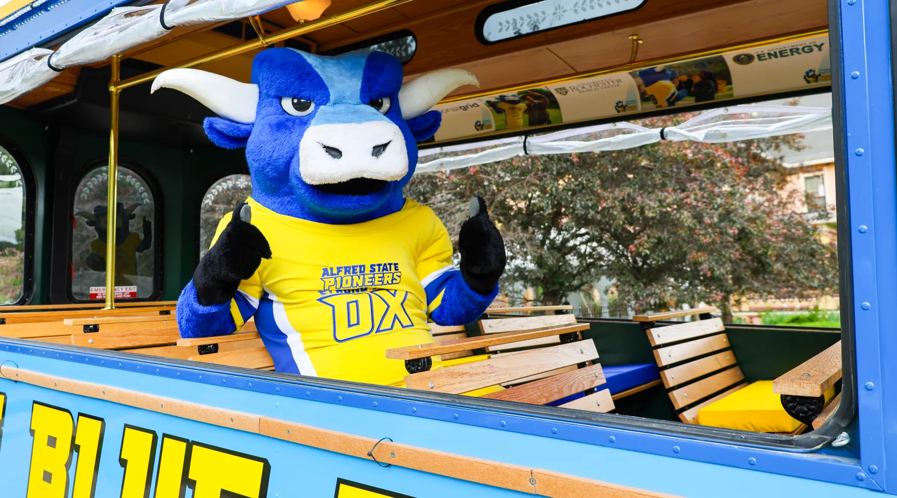 Alfred State's mascot riding on a blue trolly car.