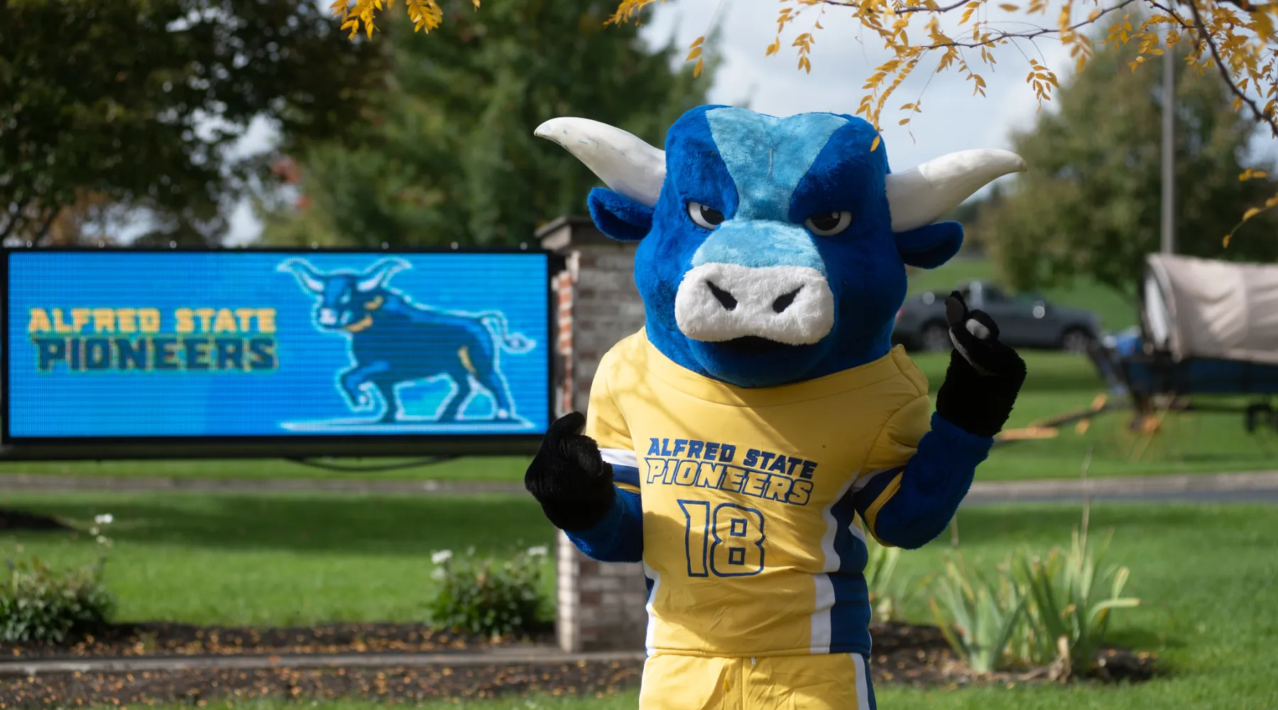 Alfred State's mascot standing in front of an electronic sign