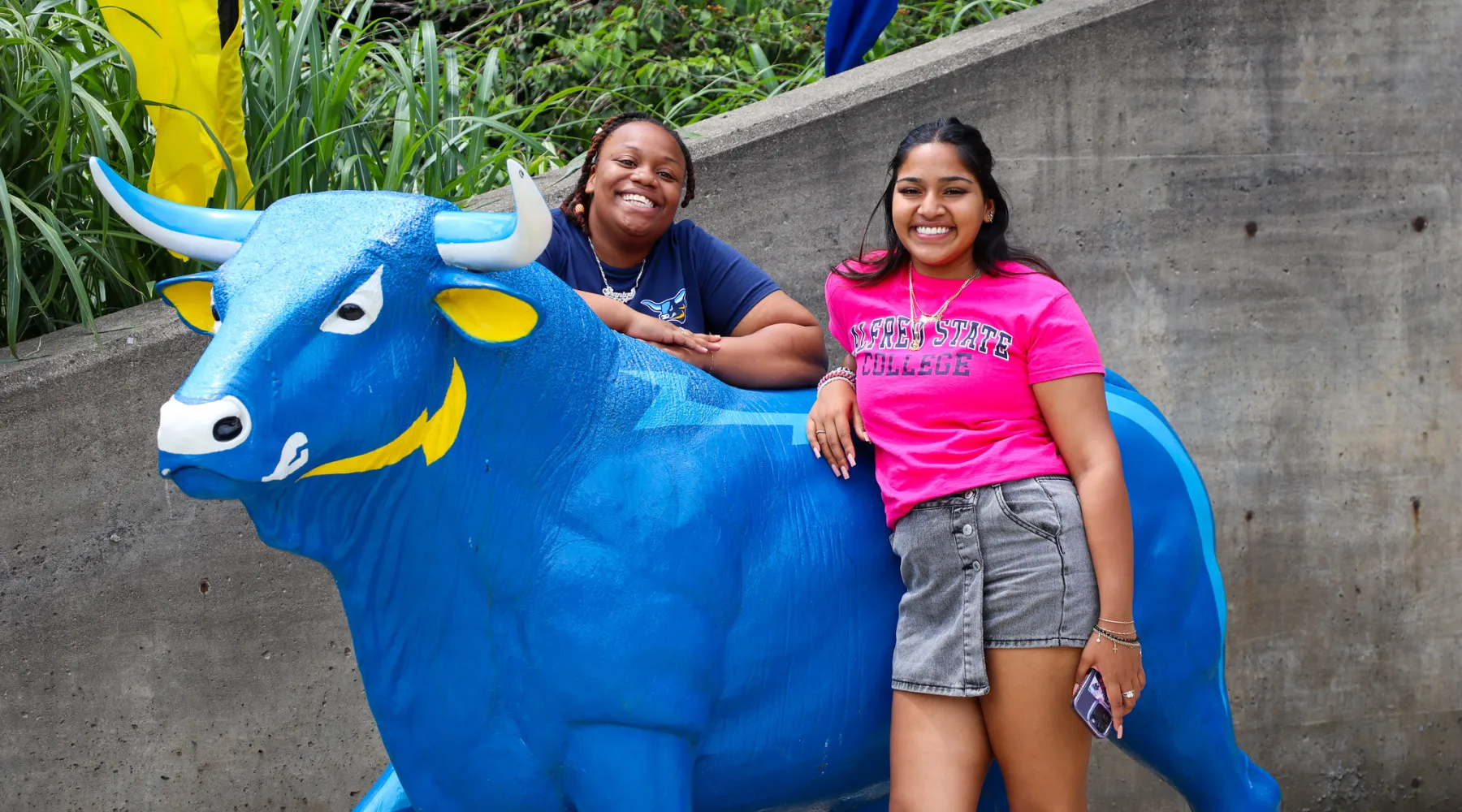 Two students standing near a statue of Alfred State's mascot, Big Blue.
