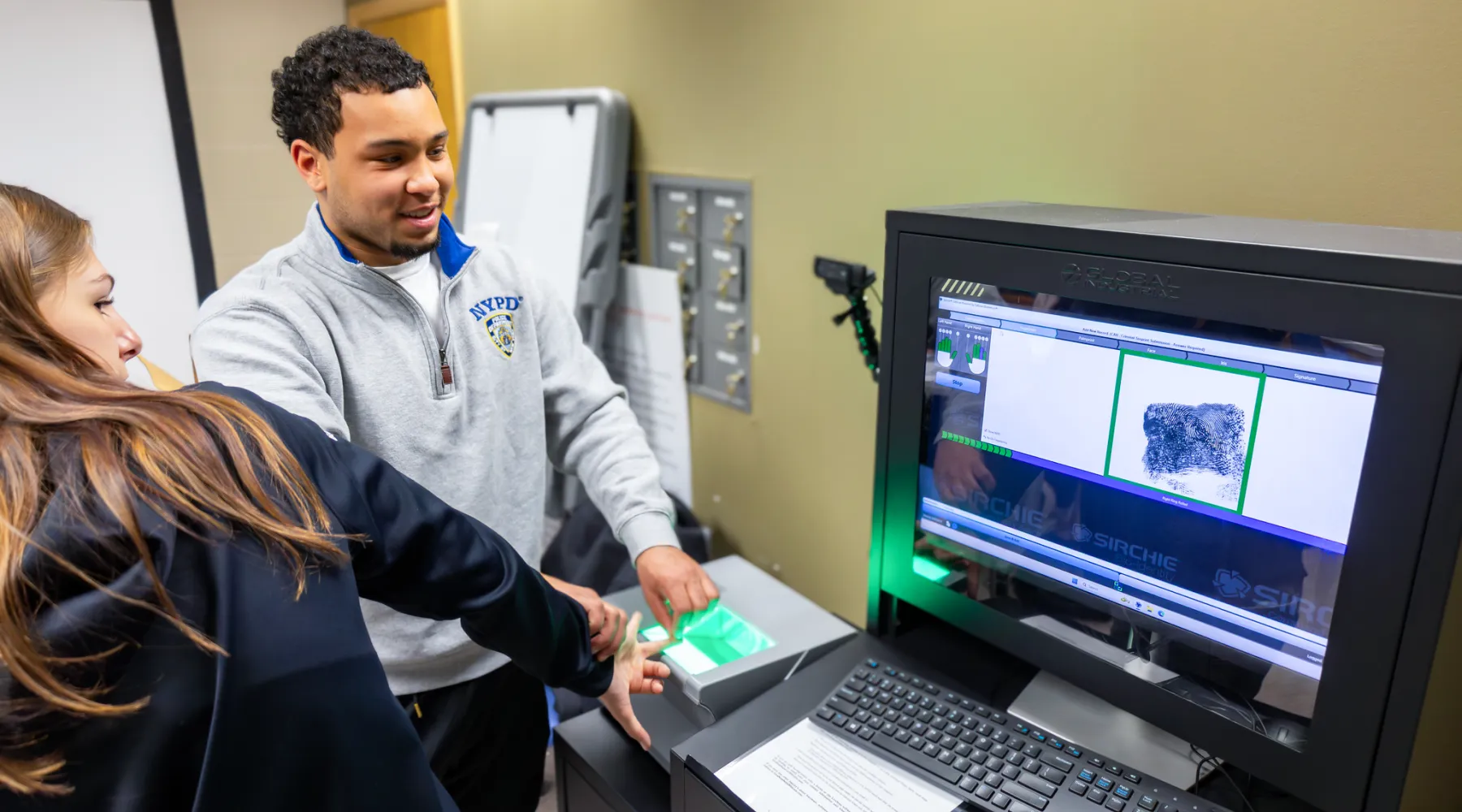 A student finger fingerprinting another student in a Forensic Science Lab.
