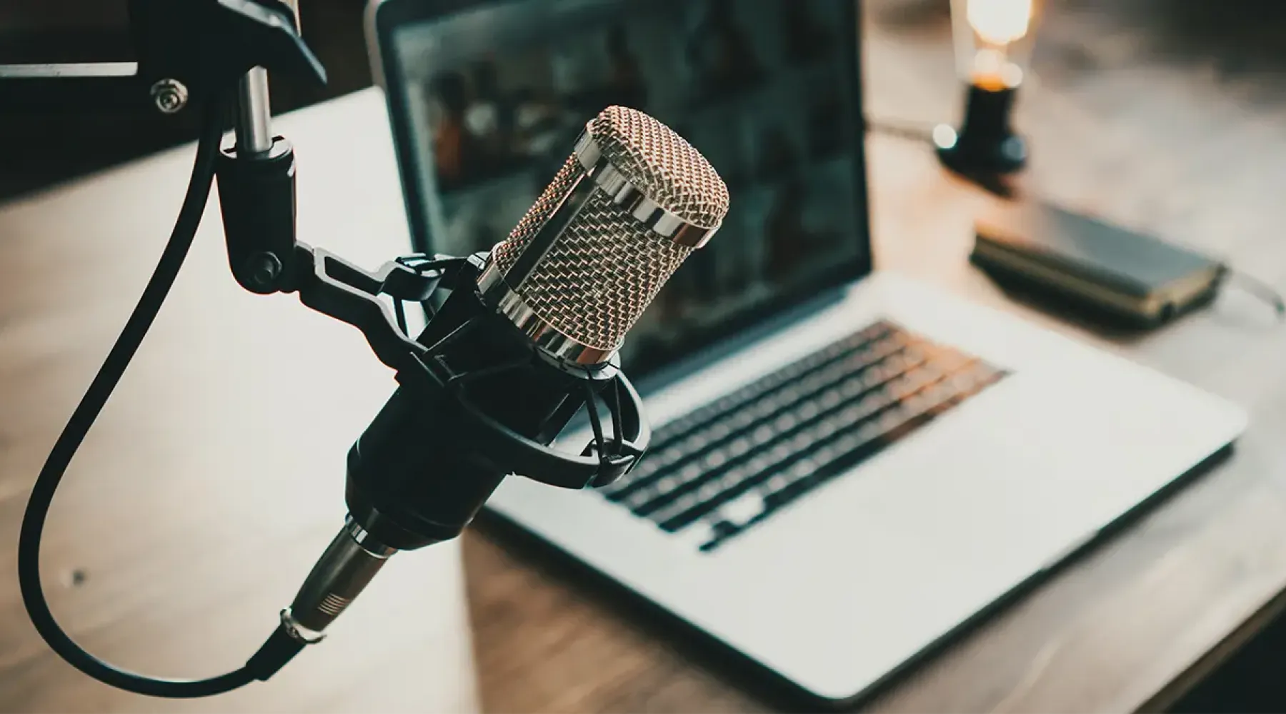 Photo of a mic with a computer in the background at a desk.